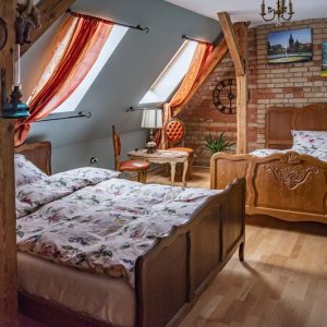 Odkryj urok Łobza! Stylowe pokoje w naszym domu zapewnią relaks po dniu pełnym zwiedzania. Pokój Zamkowy – dwa łóżka, ceglana ściana i obrazy w zabytkowym domu w Łowiskach