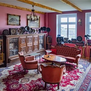 Nocleg w historycznym stylu. Nasze pokoje z antykami i dziełami sztuki oferują niepowtarzalne wrażenia. Sala Domu Kultury w Dawnym Domu – zabytkowe meble i kolekcje